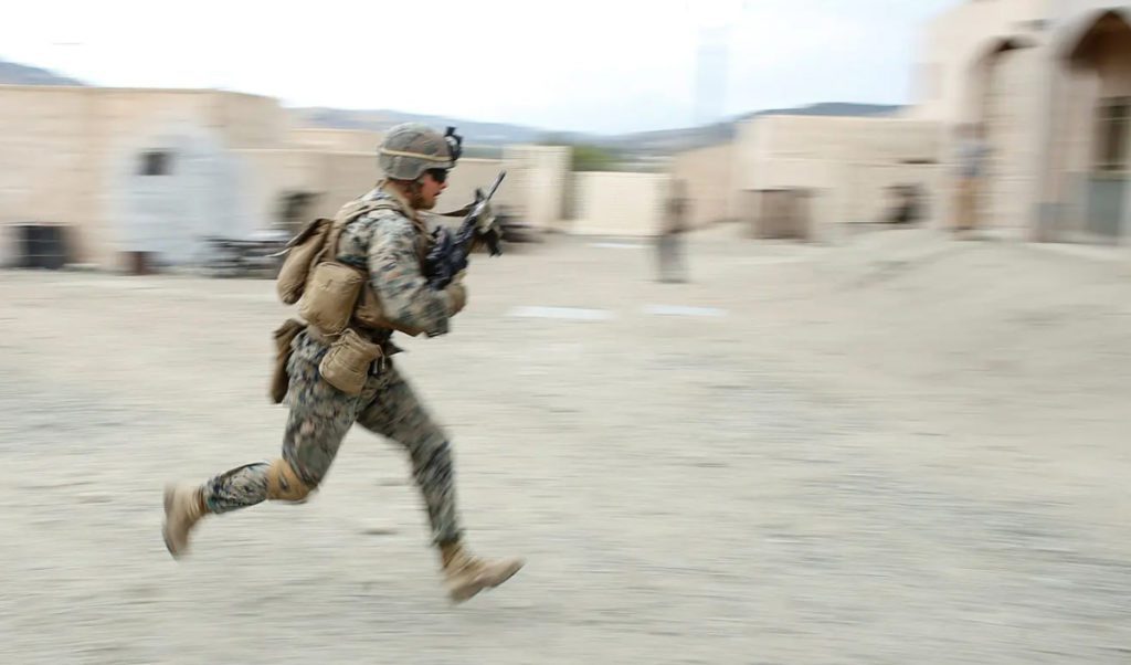 a Marine running with rifle ready