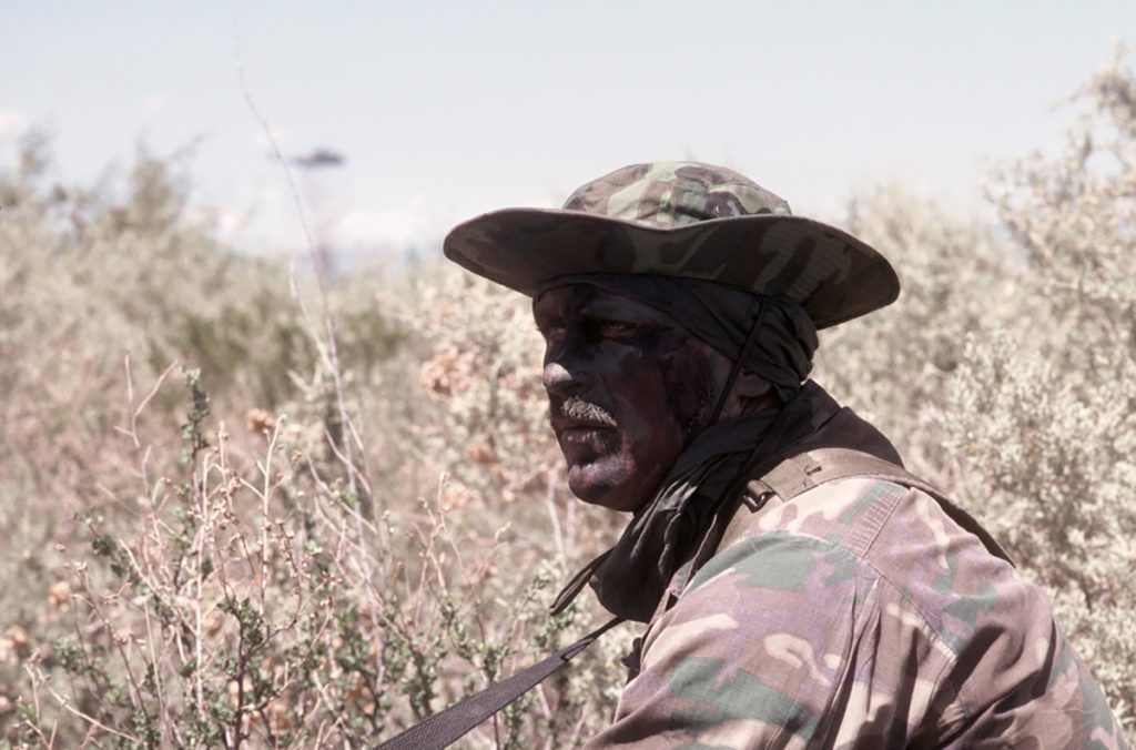 a man's face is shaded under his boonie hat