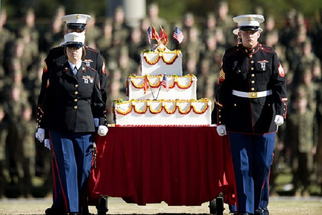 Marines in dress blues marching with birthday cake