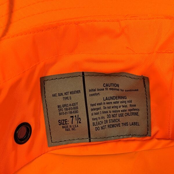 the tag of a government contractor issued hunter orange water resistant type II jungle hat