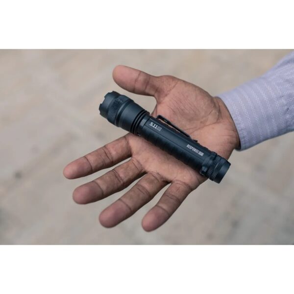 a small black tactical flashlight held in an open hand