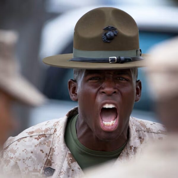 a Marine drill instructor wearing a green campaign cover and desert MARPAT cammies is yelling