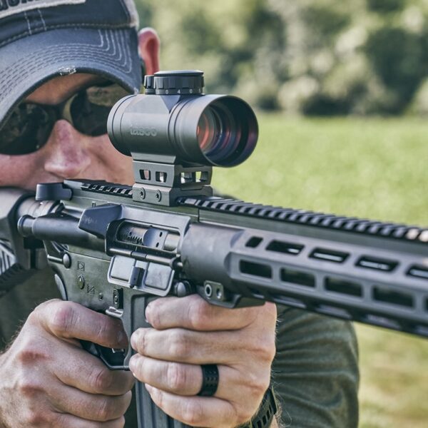 a man holding a rifle with a red dot sight